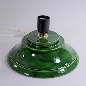 May include: A green ceramic Christmas tree stand with a black light socket and a white cord.