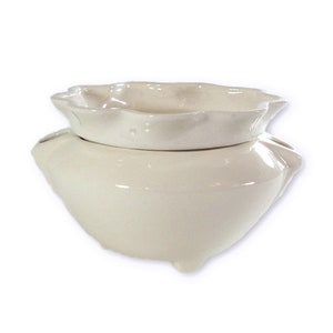 May include: White ceramic self-watering planter with a scalloped rim and three feet.