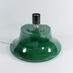 May include: A green ceramic Christmas tree stand with a black electrical socket and a white cord.