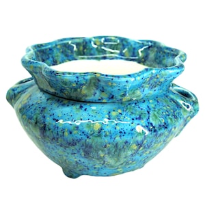 May include: A blue and green ceramic planter with a white glazed top. The planter has a speckled design and a ruffled rim.