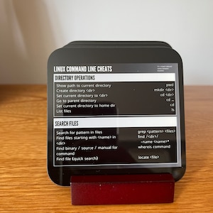May include: Black and white cheat sheet card with the title "Linux Command Line Cheats" and lists of commands for directory operations and searching files.