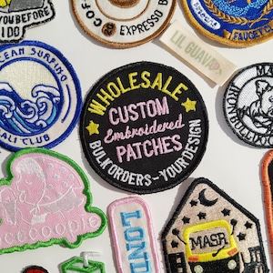 Op de afbeelding: Een verzameling van diverse geborduurde patches met uiteenlopende ontwerpen, waaronder een centrale zwarte ronde patch met gele en roze tekst die WHOLESALE CUSTOM Embroidered PATCHES BULK ORDERS-YOUR DESIGN leest en een klein LIL GUAVA stoffen label.