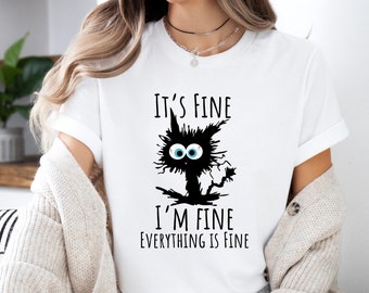 Könnte beinhalten: Weißes T-Shirt mit einer schwarzen Katzen-Grafik und dem Text "It's Fine, I'm Fine, Everything is Fine." Die Katze hat große blaue Augen. Das T-Shirt hat kurze Ärmel.
