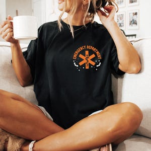 May include: A black t-shirt with an orange medical symbol and the text "Emergency Department" printed on the front.
