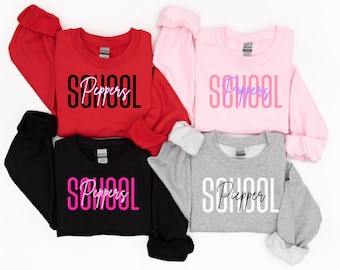 May include: Four sweatshirts in different colors with the text "School Peppers" printed on them. The sweatshirts are red, pink, black, and gray. The text is in different colors on each sweatshirt.