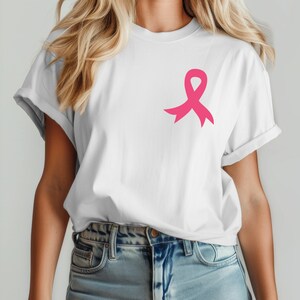 Op de afbeelding: Een wit T-shirt met een roze lint aan de linkerkant van de borst. Het lint is een symbool voor bewustwording van borstkanker.