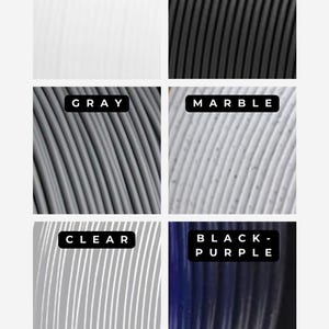 Puede incluir: Una selecci&oacute;n de seis colores diferentes de filamento para impresi&oacute;n 3D. Los colores son blanco, negro, gris, m&aacute;rmol, transparente y negro-p&uacute;rpura.