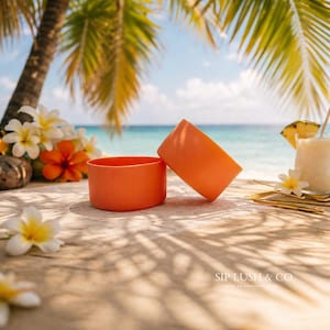 May include: Two orange tumbler sleeves on a wooden surface with a tropical beach background. The sleeves are cylindrical and made of a flexible material. The background includes palm trees, flowers, and a drink with a pineapple garnish.
