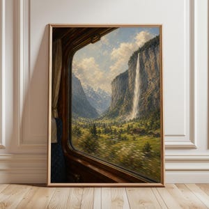 Può includere: Dipinto paesaggistico incorniciato che mostra una vista dal finestrino di un treno. L'opera presenta una cascata, una valle verde e montagne sotto un cielo nuvoloso. La cornice è di colore marrone caldo. Il dipinto evoca un senso di viaggio.