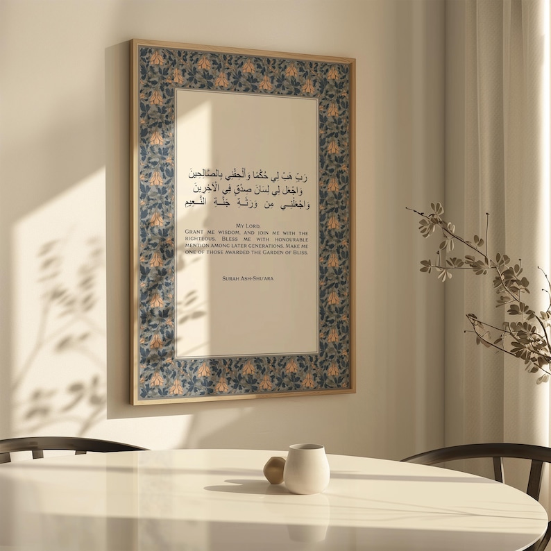 May include: Framed artwork with Arabic script and English translation. The frame has a decorative blue and gold floral pattern. The text includes the phrase "My Lord" and the title "Surah Ash-Shu'ara". The artwork is displayed on a wall.