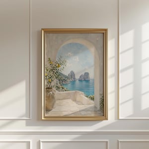 May include: A framed painting depicts a coastal scene with an archway overlooking the sea. The artwork features a lemon tree in a pot, a white terrace, and a view of the blue ocean and rock formations. The frame is gold.