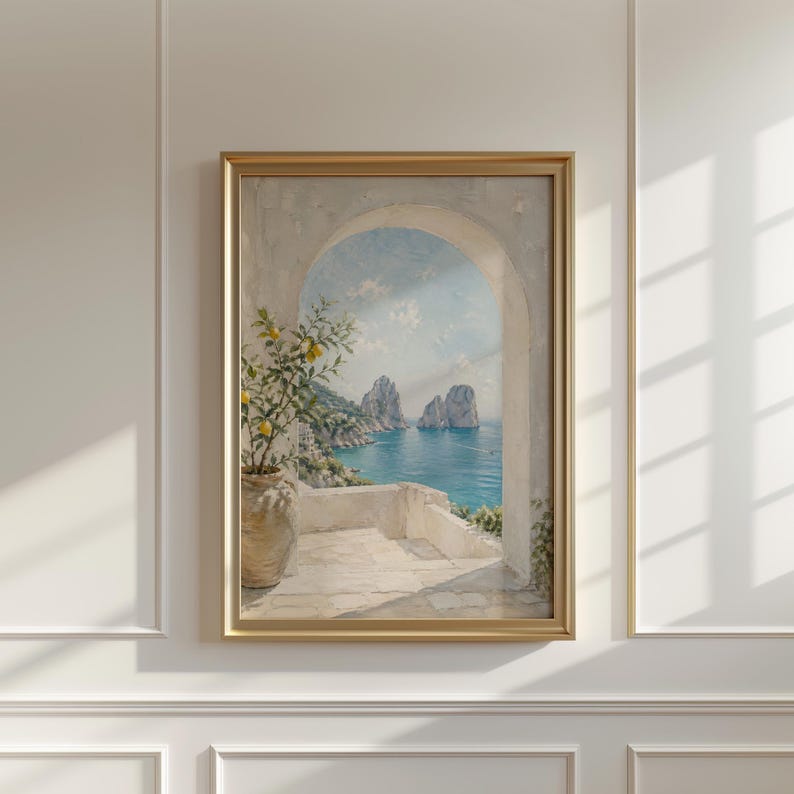 May include: A framed painting depicts a coastal scene with an archway overlooking the sea. The artwork features a lemon tree in a pot, a white terrace, and a view of the blue ocean and rock formations. The frame is gold.