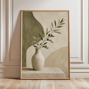 Op de afbeelding: Een ingelijste kunstdruk met een stilleven. Een witte vaas bevat olijftakken met groene bladeren en olijven. De achtergrond heeft abstracte vormen in groen en beige. De lijst is lichtbruin.