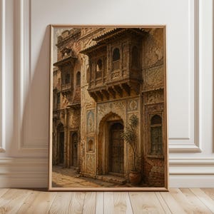 May include: A framed watercolor print of an old building with ornate wooden balconies and arched doorways. The building's facade is a mix of beige, brown, and red hues, with intricate carvings and details. A small potted plant sits near the entrance.