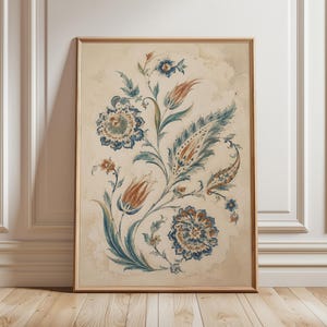 May include: A framed vertical wall art print featuring a watercolor-style botanical illustration. The design displays intricate blue and rust-orange floral motifs, including stylized tulips and circular blossoms, set against a cream background.