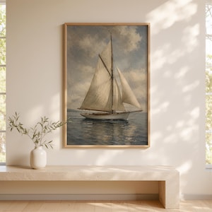 May include: A framed nautical painting depicts a sailboat on the water under a cloudy sky. The sailboat has white sails and a wooden hull. The frame is a light brown color. The painting is displayed on a wall above a neutral-colored bench.