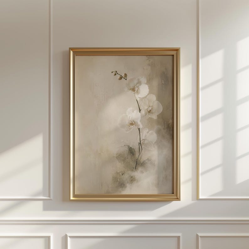K&ouml;nnte beinhalten: Ein gerahmter Wandkunstdruck, der einen zarten wei&szlig;en Orchideenzweig vor einem weichen, neutralen Hintergrund mit texturierten, malerischen Pinselstrichen zeigt. Das Kunstwerk ist in einem d&uuml;nnen, goldfarbenen Metallrahmen eingefasst.
