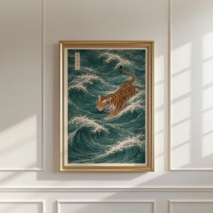 May include: Framed art print featuring a tiger swimming through teal waves. The tiger has orange and black stripes. The artwork is in a gold frame and has Japanese text in the upper left corner.