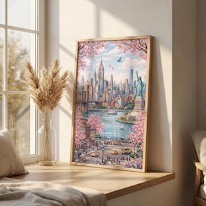 Op de afbeelding: Een ingelijste kunstdruk van New York City, met het Empire State Building, het Vrijheidsbeeld en de Brooklyn Bridge. Het kunstwerk is omgeven door roze kersenbloesem, met gele taxi's en boten op het water.