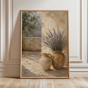 Può includere: Una stampa incorniciata di una natura morta. Due vasi di terracotta sono su un patio in pietra, uno pieno di lavanda viola. Lo sfondo presenta un muro usurato e fogliame, il tutto baciato dal sole.
