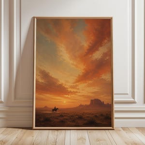 Può includere: Una stampa d'arte da parete verticale incorniciata che raffigura un cavaliere solitario a cavallo in un vasto paesaggio desertico al tramonto. Il cielo è pieno di nuvole arancioni e dorate sopra mesas lontane e vegetazione sotto il sole.