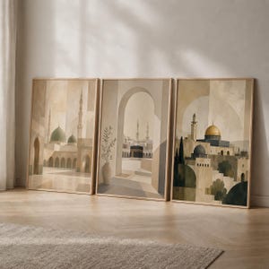 May include: A set of three framed wall art prints featuring architectural illustrations of Islamic landmarks in neutral beige and brown tones. The prints depict mosque structures, minarets, the Kaaba, and the Dome of the Rock with geometric arches.