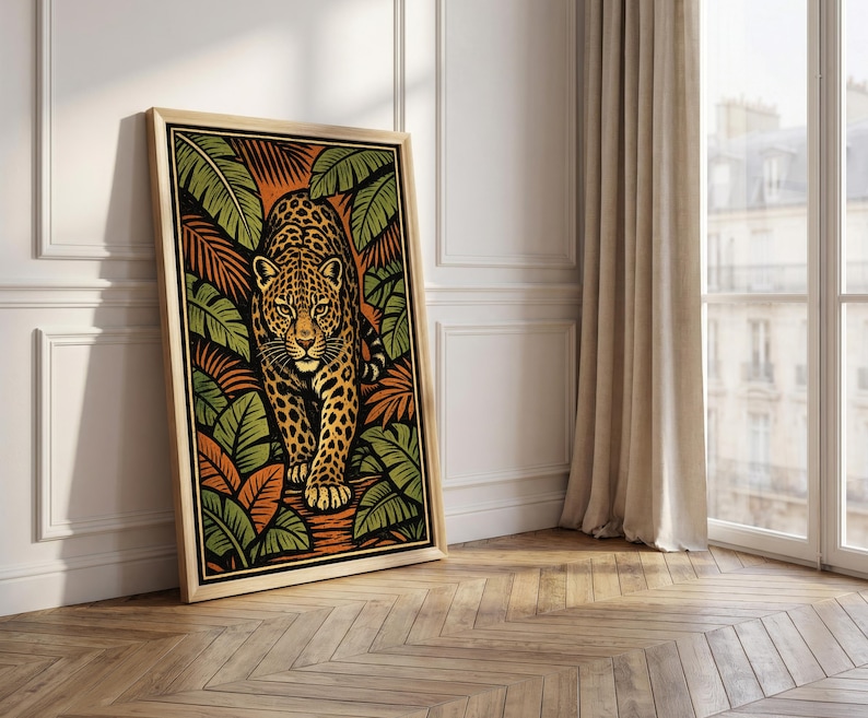 May include: A framed art print featuring a stylized leopard walking forward. The artwork uses a palette of orange, green, and black, with the leopard's spots and the surrounding foliage adding detail. The frame is a light wood color.
