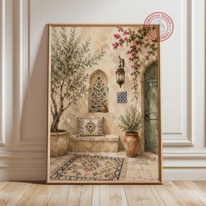 Peut inclure: Une impression d'art mural encadrée représentant une cour méditerranéenne avec un banc en pierre, un olivier en pot, un tapis à motifs, une lanterne suspendue, une porte cintrée bleue et des fleurs de bougainvillier rose sur un mur beige.