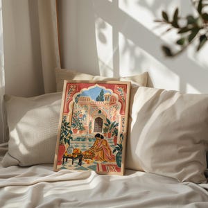 May include: A framed art print featuring a colorful illustration of a person in a yellow garment kneeling in a courtyard with a fountain, potted plants, and an arched doorway. The scene includes a small table with bowls of fruit and blue tile floors.