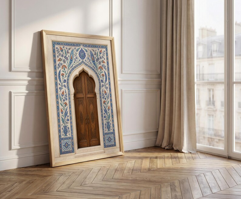 Puede incluir: Una obra de arte enmarcada que presenta una puerta de madera con una parte superior arqueada, enmarcada en un borde decorativo de patrones florales azules, naranjas y blancos. La obra de arte est&aacute; apoyada contra una pared blanca, con un suelo de madera en primer plano.