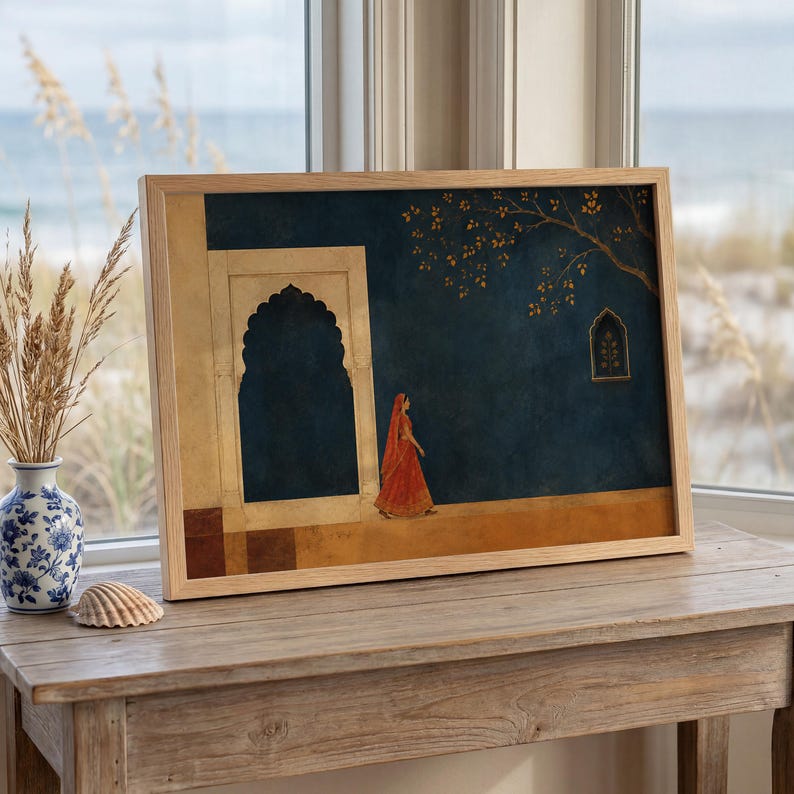 May include: A framed rectangular wall art print featuring a dark blue wall with a large arched doorway and a small window. A figure in a vibrant orange garment walks across the foreground. The scene includes a tree branch with gold leaves.
