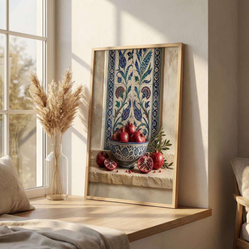 May include: A framed print featuring a still life with pomegranates. A decorative bowl filled with ripe pomegranates sits on a stone ledge. The background includes a patterned tile design in blue, green, and white, with a wooden frame.