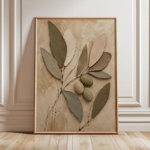 May include: A framed wall art piece featuring a textured, three-dimensional relief of an olive branch. The artwork displays elongated leaves in shades of sage green, beige, and taupe, alongside three oval-shaped olives in muted earth tones.