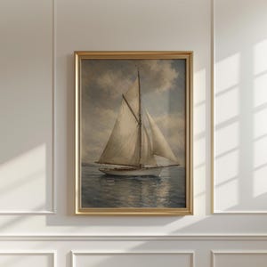 May include: A framed nautical painting depicts a sailboat on the water under a cloudy sky. The sailboat has white sails and a white hull. The painting is in a gold frame, adding a touch of elegance to the artwork.