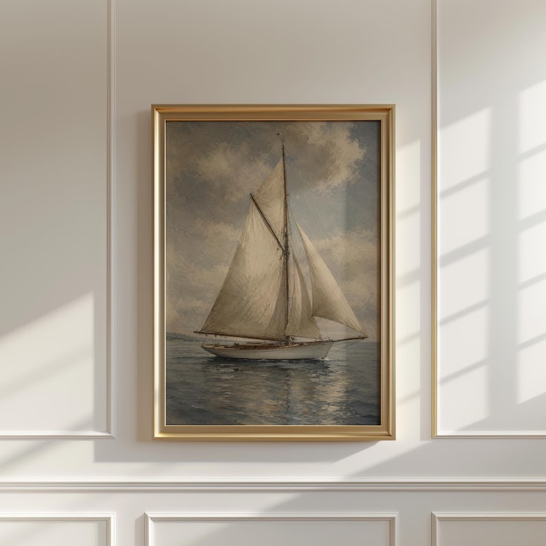 May include: A framed nautical painting depicts a sailboat on the water under a cloudy sky. The sailboat has white sails and a white hull. The painting is in a gold frame, adding a touch of elegance to the artwork.