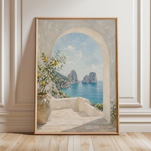 May include: Framed art print of a coastal scene. The painting depicts a white arched doorway overlooking a turquoise sea with rock formations. A potted lemon tree with yellow fruit sits on a white terrace. The artwork is in a wooden frame.