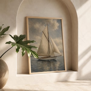 May include: A framed print of a sailboat on the water. The artwork features a classic sailboat with white sails against a cloudy sky. The frame is a light wood color, and the overall aesthetic is vintage.