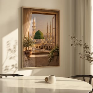 May include: A framed print depicts a view of a mosque with a green dome and minarets, seen through a window. The artwork is set in a room with a table and a plant in a pot. The window is open, and a curtain is visible.