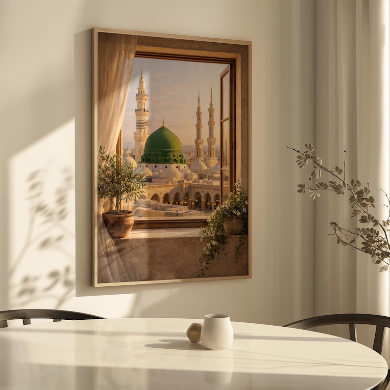 May include: A framed print depicts a view of a mosque with a green dome and minarets, seen through a window. The artwork is set in a room with a table and a plant in a pot. The window is open, and a curtain is visible.