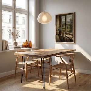 May include: A dining room scene featuring a wooden table with black hairpin legs and four wooden chairs. A framed painting hangs on the wall, and a light fixture hangs above the table. A window with a view is visible.