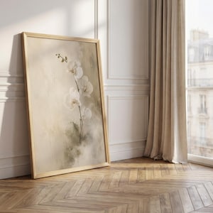 K&ouml;nnte beinhalten: Ein gerahmter vertikaler Wandkunstdruck, der einen zarten wei&szlig;en Orchideenzweig mit mehreren Bl&uuml;ten vor einem weichen, neutralen, abstrakt bemalten Hintergrund mit ged&auml;mpften beigen und salbeigr&uuml;nen Pinselstrichen in einem hellen Holzrahmen zeigt.