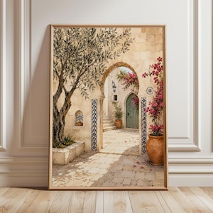 May include: A framed wall art print depicting a Mediterranean courtyard scene with a stone archway, a gnarled olive tree, a terracotta pot filled with vibrant pink bougainvillea flowers, blue and white patterned tile accents, and a green door.