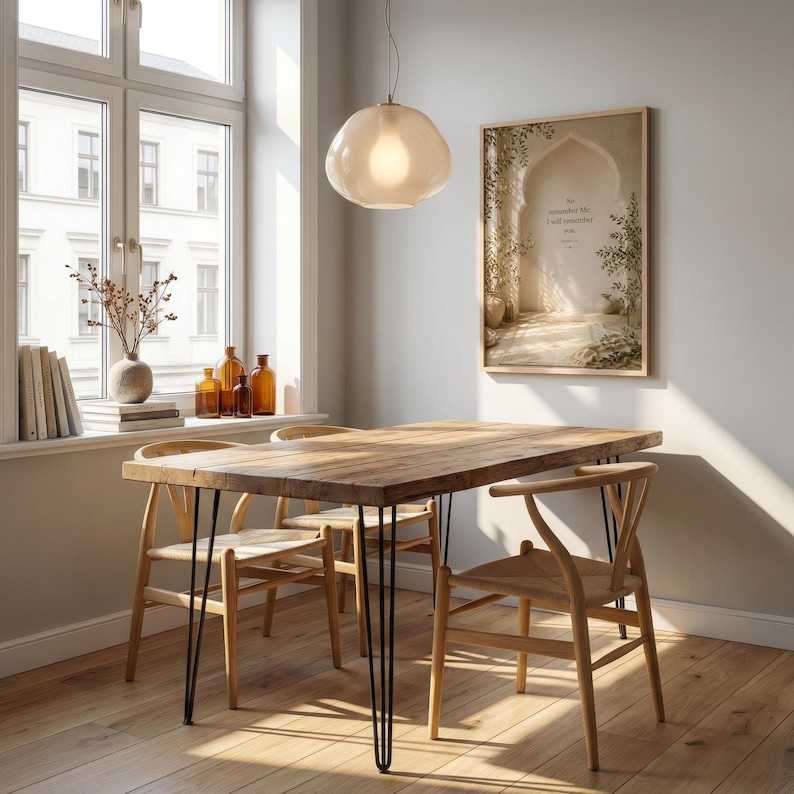 May include: A rustic wooden dining table with black hairpin legs and four wooden chairs. A large window with a view of a building is in the background. A framed picture hangs on the wall, and a light fixture hangs above the table.