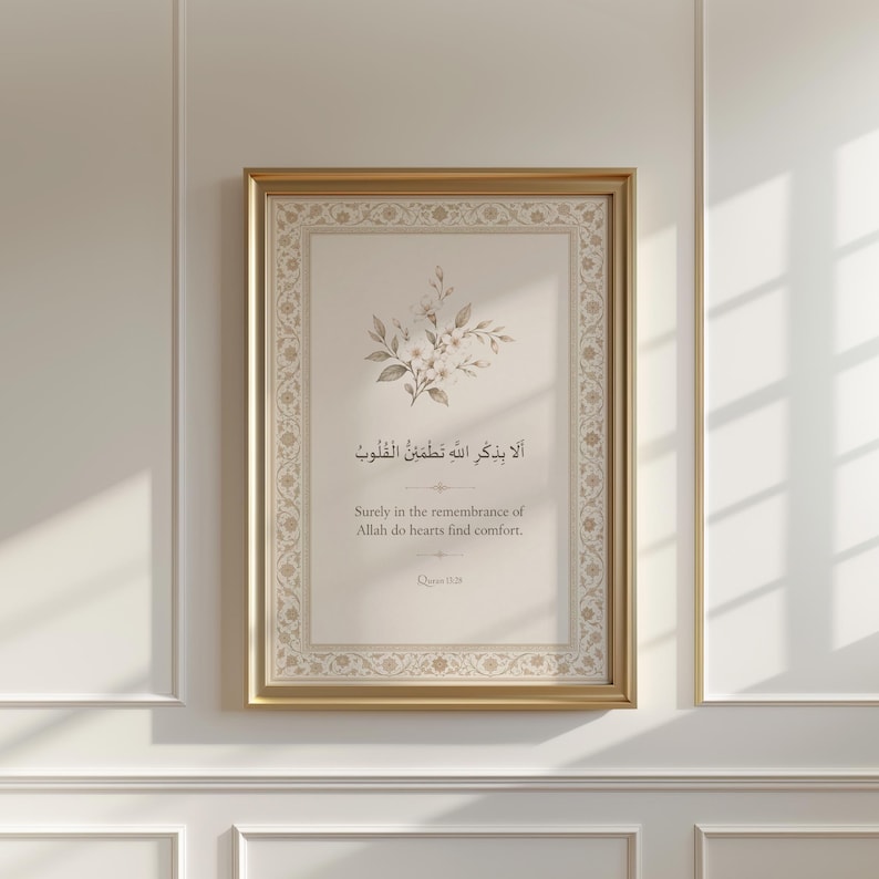 May include: A framed print with a gold-coloured border, displaying Arabic calligraphy and English text. The artwork incorporates a floral design at the top. The English text states, "Surely in the remembrance of Allah do hearts find comfort."
