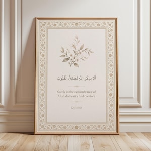 May include: A framed print with Arabic calligraphy and English text. The artwork features a floral design. The text reads "Surely in the remembrance of Allah do hearts find comfort." The frame is a warm brown colour.
