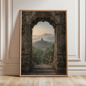 May include: Framed print of a temple complex viewed through an ornate stone archway. The image features a detailed architectural structure with intricate carvings, leading to a lush green landscape and distant mountains. The artwork is set in a wooden frame.