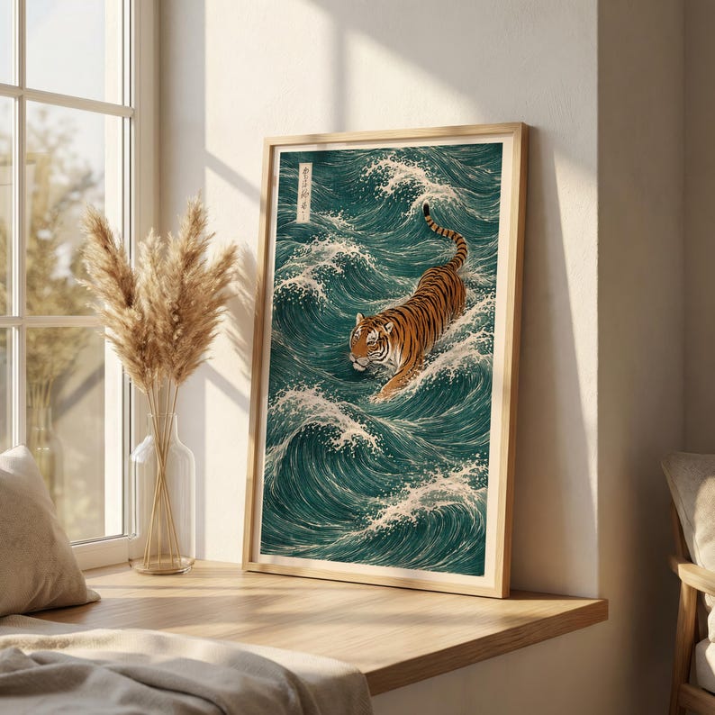 May include: Framed art print featuring a tiger in a teal ocean with white waves. The tiger has orange and black stripes. The artwork is in a light wood frame and is displayed on a wooden ledge near a window.
