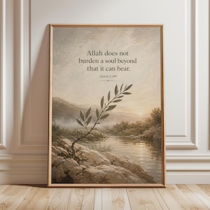 May include: Framed art print featuring a serene landscape with a body of water and mountains. The artwork includes the text "Allah does not burden a soul beyond that it can bear. Quran 2:286" in a classic font. The print is in a wooden frame.