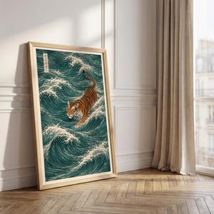 May include: A framed art print depicts a tiger wading through ocean waves. The artwork features a tiger with orange and black stripes, set against a backdrop of teal waves with white crests. The frame is a light wood color.