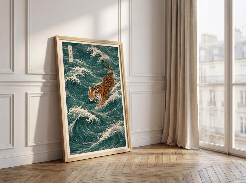 May include: A framed art print depicts a tiger wading through ocean waves. The artwork features a tiger with orange and black stripes, set against a backdrop of teal waves with white crests. The frame is a light wood color.